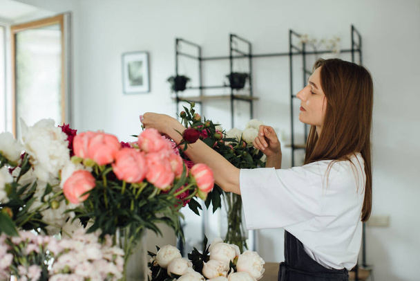 Bloemist vrouw in de werkruimte van de bloemenwinkel. - stockfoto - Foto, afbeelding