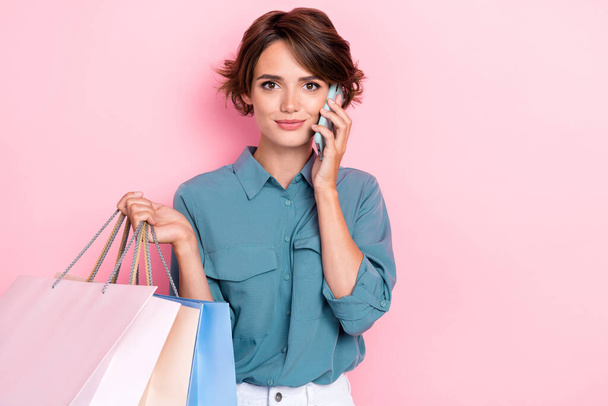 Portrait of charming attractive girl speak chatting telephone hold bags isolated on pink color background. - Foto, imagen