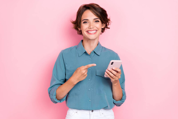 Photo of young pretty adorable cute pretty attractive nice smiling woman finger pointing showing her new smartphone ad app isolated on pink color background. - Photo, Image
