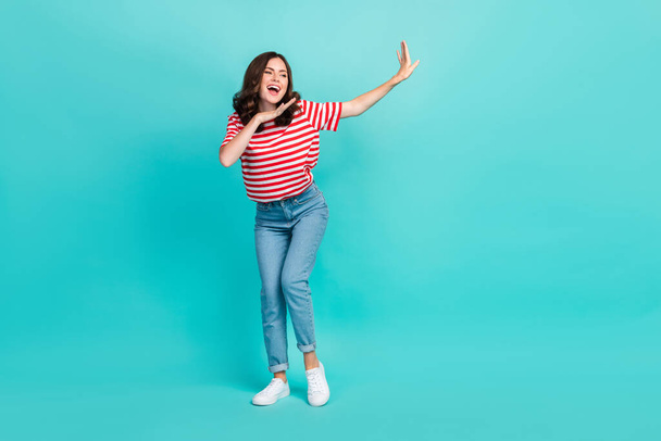 Full length photo of cheerful lovely lady enjoy hobby look empty space wear striped trendy outfit isolated on cyan color background. - Fotografie, Obrázek