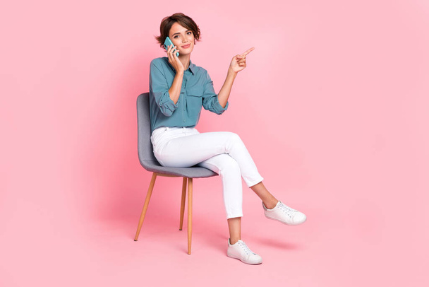 Photo of pretty calm lady sit chair finger direct empty space offer buy modern telephone device gadget isolated on pink color background. - 写真・画像