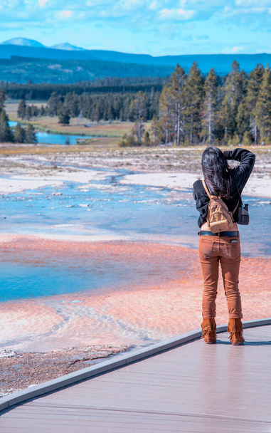 Achteraanzicht van vrouwelijke toerist die foto 's neemt van Yellowstone National Park. - Foto, afbeelding