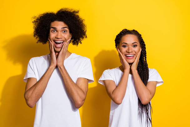Portrait of two astonished crazy people hands touch cheeks open mouth isolated on yellow color background. - Foto, Imagen