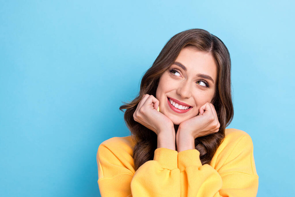 Closeup photo of young positive pretty gorgeous lady dreamy look empty space wear yellow sweater touch cheeks new advert isolated on blue color background. - Φωτογραφία, εικόνα