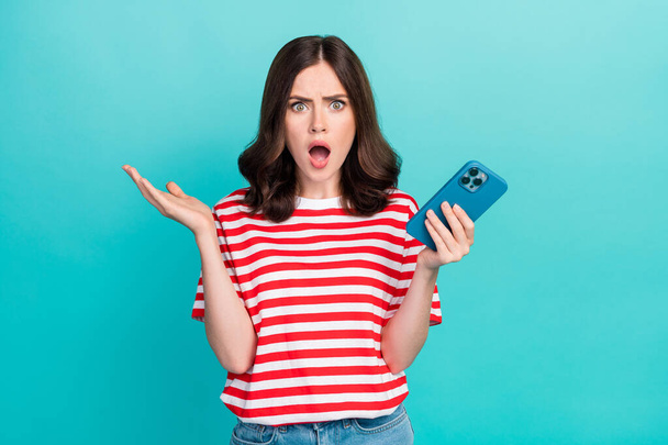 Photo of amazed surprised girl dressed red t-shirt getting message modern gadget isolated teal color background. - Foto, imagen