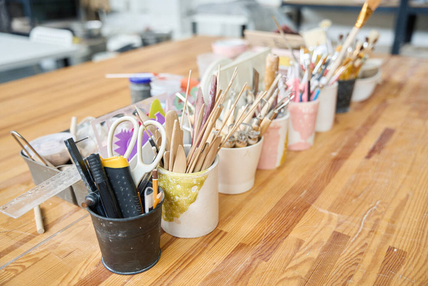 Tool kits, brushes, spatulas, sponges, for manual labor in cups on a wooden table - 写真・画像