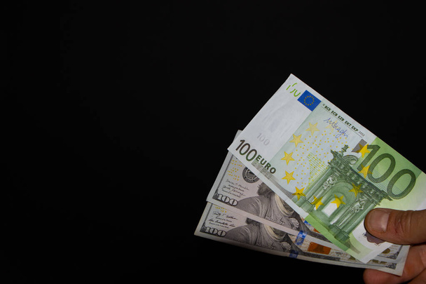 Portafogli Destro Pila da due banconote da 100 Dollari e da 100 euro Banconota su sfondo nero, La banconota da 100 Dollari viene trasferita a mano - Foto, immagini