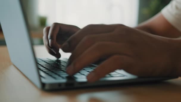 Закрыть руки мужчины неузнаваемого африканского латиноамериканца за столом, печатающего клавиатуру ноутбука онлайн, изучающего удалённую работу с компьютерным приложением, бизнес-чаты с текстовым криптовалютным проектом в сети - Кадры, видео