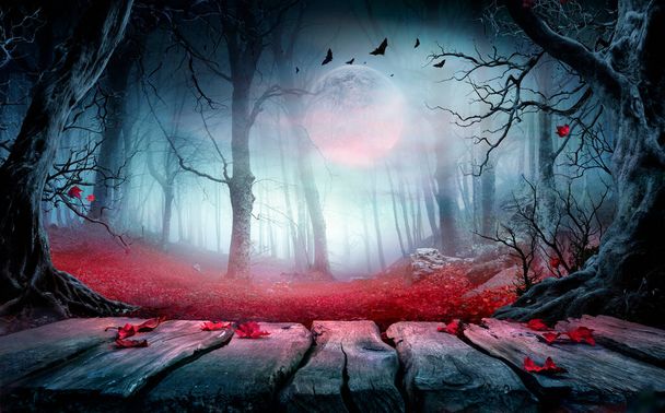 Halloween - Mesa de madeira na floresta assustadora à noite com folhas vermelhas na paisagem de outono ao luar - Foto, Imagem