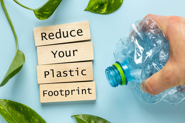 El ezici plastik şişe, ahşap blok kaydediliyor, plastik ayak izini azalt, çevre konseptini azalt, plastik atıkları geri dönüştür, plastik üretimini azalt - Fotoğraf, Görsel