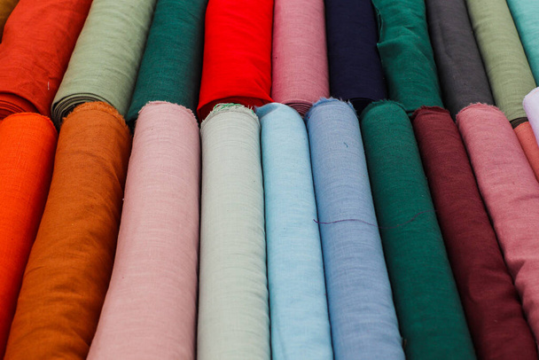 Detailed close up view on samples of cloth and fabrics in different colors found at a fabrics market. - Foto, Imagem