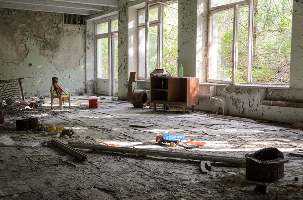 Sala giochi in un edificio Prypiat. Una bambola decapitata giace su una sedia rossa rotta accanto a un sedile vuoto. Zona di esclusione di Chernobyl, Ucraina. Foto di alta qualità - Foto, immagini
