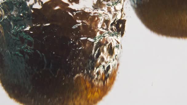 Detailní kiwi cákají vodu v bublinách. Sladké tropické ovoce kapající tekutiny mytí v lehkém pozadí. Chutný organický produkt pro letní detoxikační vaření. Zdravý životní styl veganské výživy koncept - Záběry, video