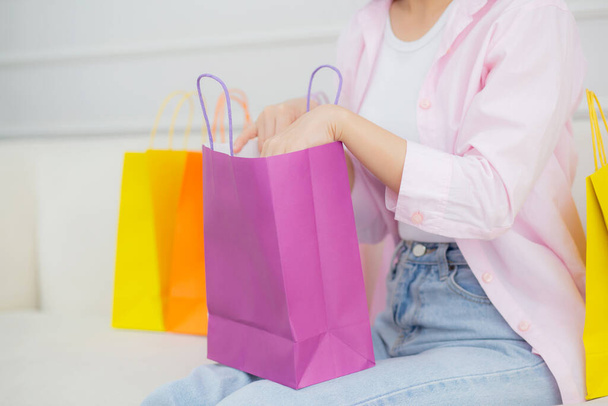 Closeup hands of woman sitting on sofa open paper bag while online shopping with credit card at home, girl purchase and discount of consumer with excited, shopaholic and lifestyles concept. - Photo, Image