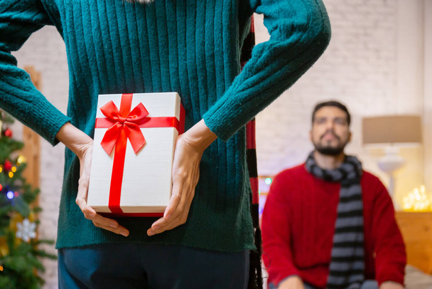 Молода біла жінка ховає подарунки для сюрпризного хлопця у святкуванні Різдва вдома, жінка тримає подарунок схованки для того, щоб дати чоловікові збуджений, різдвяний і новорічний або святковий концепції
. - Фото, зображення
