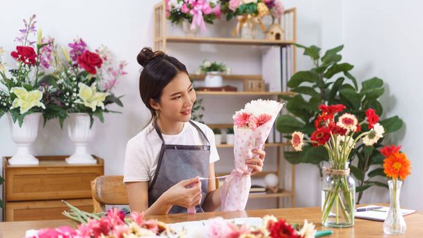 Florist Konzept, weibliche Floristin lächeln und halten bunten Blumenstrauß mit Papier und Schleife. - Foto, Bild