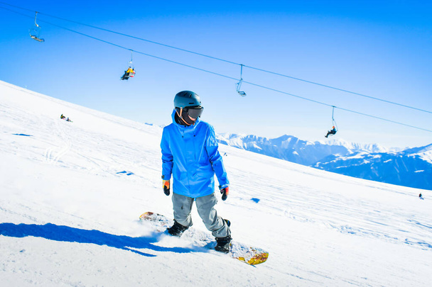 Joven paseo snowboarder cuesta abajo en las montañas escénicas del Cáucaso en el movimiento de congelación rápida empinada cuesta abajo solo - Foto, Imagen