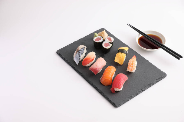 Sushi-Set Nigiri und Sushi-Rollen mit Sojasauce und Essstäbchen japanisches Essen isoliert vor weißem Hintergrund - Foto, Bild
