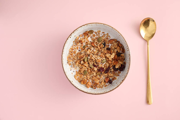 granola con leche con cuchara aislada en fondo rosa - Foto, Imagen