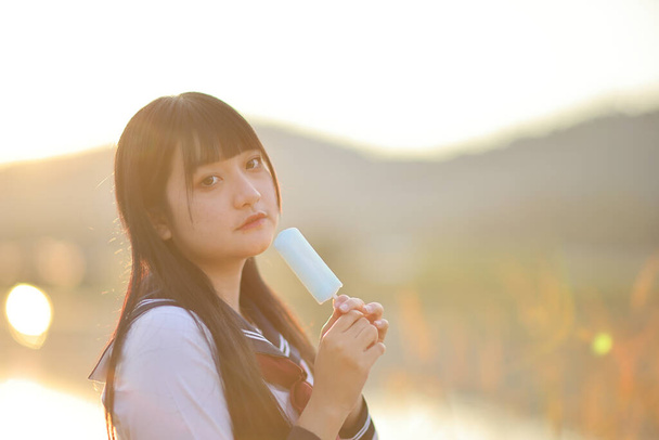 Asiático High School Girls estudante comer sorvete no campo com nascer do sol - Foto, Imagem