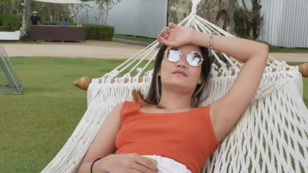aziatische vrouw ontspannen en op hangmat in de buurt van strand onder kokosnoot boom in vakantie - Video