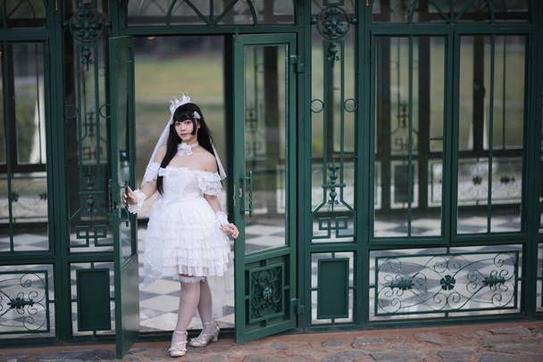 Piękna młoda kobieta z białą sukienką lolita z europejskim ogrodem Japońska moda - Zdjęcie, obraz