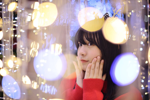 Mooie Aziatische jonge vrouw met een rode trui met kerstboom licht - Foto, afbeelding