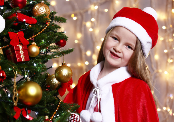 Little girl near Christmas tree on bright background - Photo, image