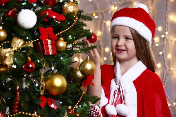 Little girl near Christmas tree on bright background - 写真・画像