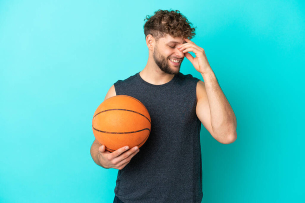 Bonito jovem jogando basquete isolado no fundo azul rindo - Foto, Imagem