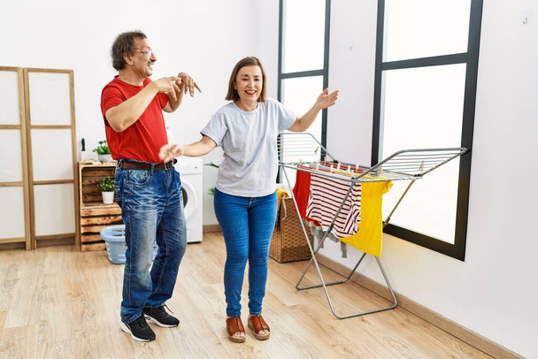 Чоловік і жінка середнього віку танцюють в очікуванні пральної машини в пральні
 - Фото, зображення