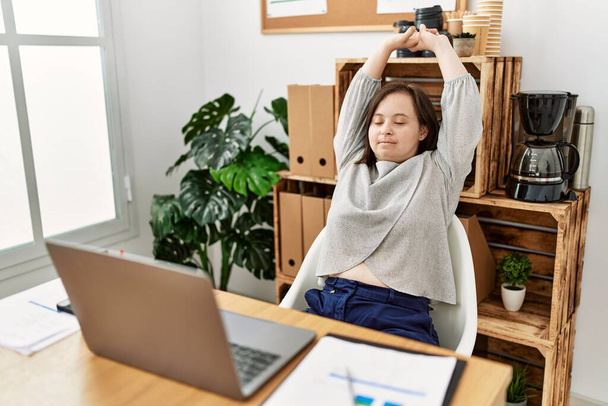 Brunette woman with down syndrome stretching arms relaxing at business office - Photo, Image