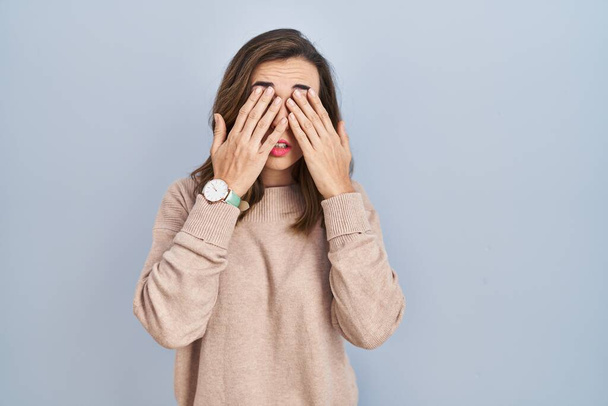 Jonge vrouw staat over geïsoleerde achtergrond wrijven ogen voor vermoeidheid en hoofdpijn, slaperige en vermoeide uitdrukking. gezichtsproblemen  - Foto, afbeelding