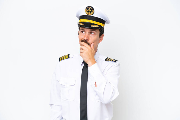 Airplane caucasian pilot isolated on white background having doubts and with confuse face expression - Foto, Imagem