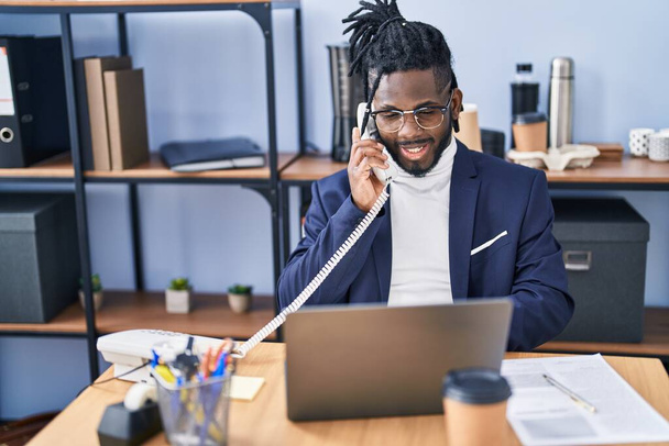 Afroamerykanka kobieta biznes pracownik za pomocą laptopa rozmowy przez telefon w biurze - Zdjęcie, obraz