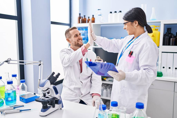 Άνδρας και γυναίκα με στολή επιστήμονα. Κόλλα πέντε με τα χέρια σηκωμένα στο εργαστήριο. - Φωτογραφία, εικόνα