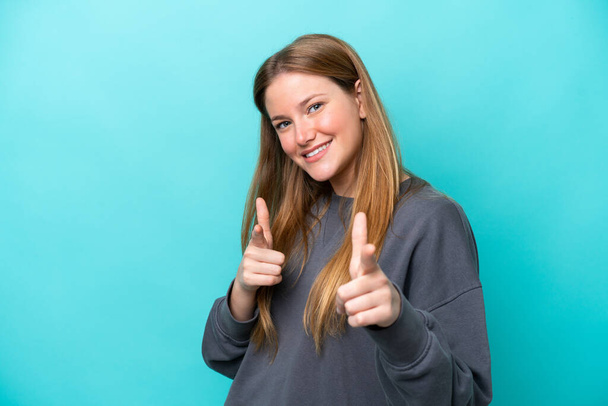 Young caucasian woman isolated on blue background pointing to the front and smiling - Foto, imagen