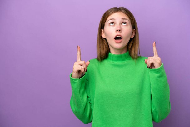 Young English woman isolated on purple background surprised and pointing up - Foto, Imagem