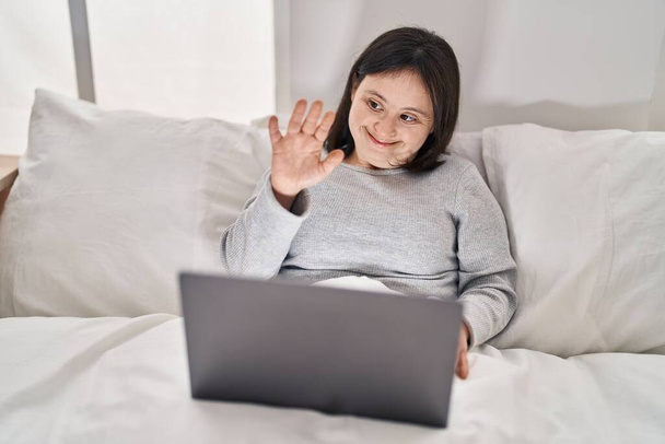 Fiatal nő lefelé szindróma, amelynek videohívás ül az ágyon a hálószobában - Fotó, kép
