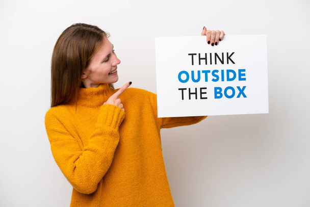 Nuori Englanti nainen eristetty valkoisella taustalla tilalla kyltti tekstiä Ajattele ulkopuolella Box ja osoittaa sitä - Valokuva, kuva