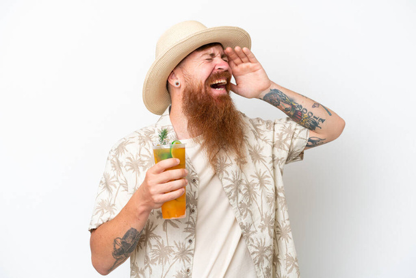 Homem ruivo com barba longa bebendo um coquetel em uma praia isolada no fundo branco sorrindo muito - Foto, Imagem