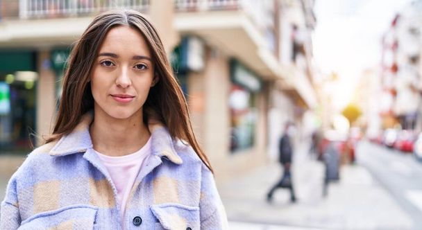 Fiatal gyönyörű spanyol nő áll komoly kifejezés az utcán - Fotó, kép