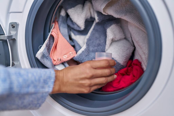 Junge Frau schüttet Waschmittel in Waschküche auf Waschmaschine - Foto, Bild