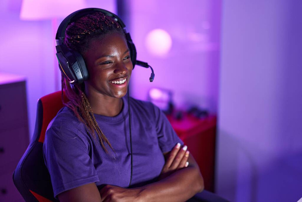 African american woman streamer smiling confident sitting with arms crossed gesture at gaming room - Valokuva, kuva