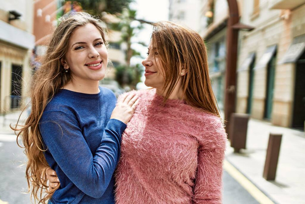 Madre e figlia sorridenti fiduciosi abbracciarsi in strada - Foto, immagini