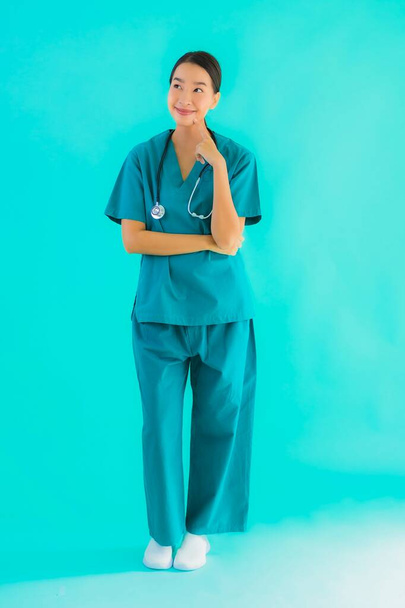 portret piękny młody Azji lekarz kobieta uśmiech z wiele akcja na niebieski odizolowane tło - Zdjęcie, obraz