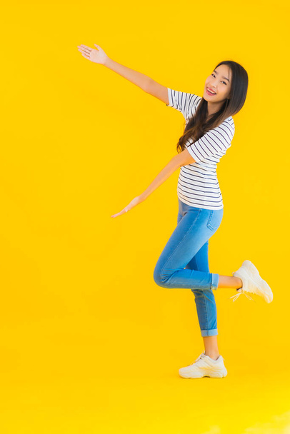 Ritratto bella giovane donna asiatica sorriso felice con azione su sfondo giallo isolato - Foto, immagini
