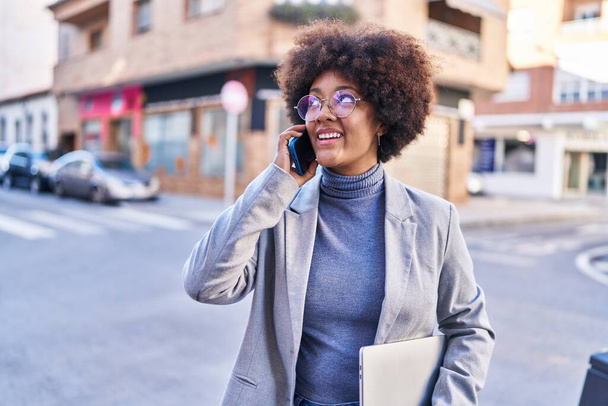 Afrikai amerikai nő végrehajtó beszél okostelefon gazdaság laptop az utcán - Fotó, kép
