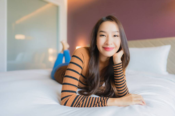 Ritratto bella giovane donna asiatica sorriso rilassarsi sul letto in camera da letto interno - Foto, immagini
