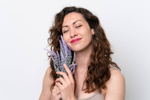 Junge kaukasische Frau isoliert auf weißem Hintergrund mit einer Lavendelpflanze. Porträt aus nächster Nähe - Foto, Bild